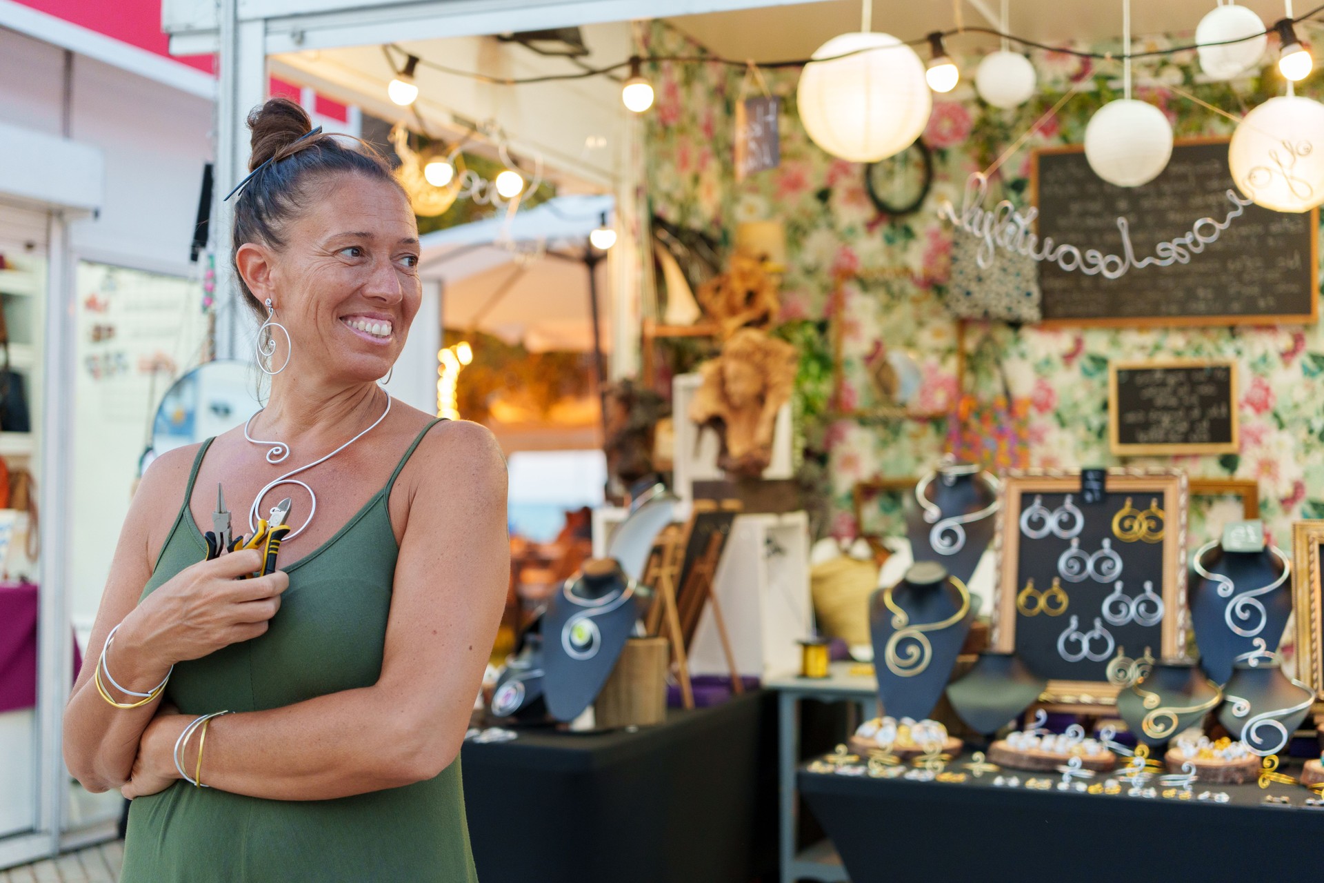 Proud Hispanic Woman in Her 50s Posing in Front of Her Street Stall Selling Handmade Aluminum Wire Jewelry